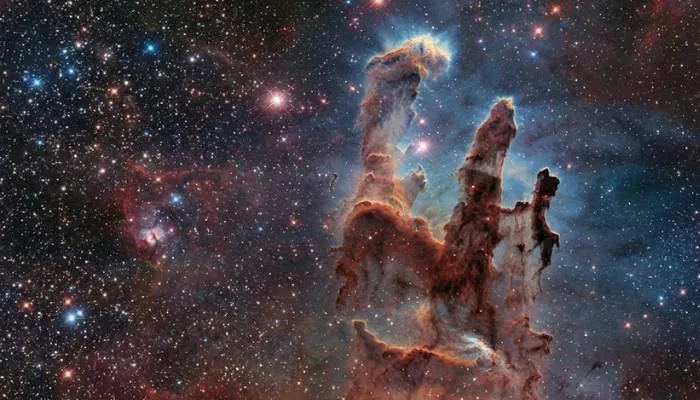 Wide-angle shot of the Pillars of Creation showing dense dust and gas structures in a stellar nursery.