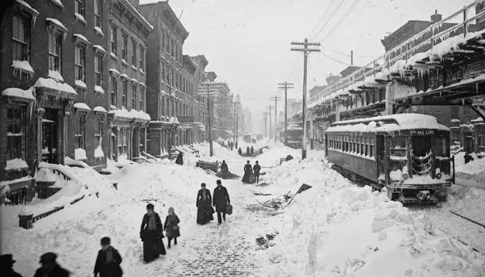 Historical photograph of snow-covered streets, buried houses, and stranded train cars in New York City after the Great White Hurricane of March 1888.