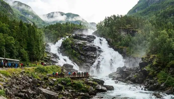 The rushing white waters of Kjos Fossen waterfall cascading over dark, rugged rocks in Norway.